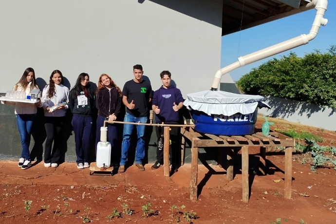 Foto de grupo de estudantes com o experimento de coleta e tratamento de água