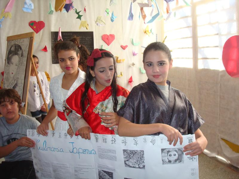 Alunas a caráter expondo materiais da cultura japonesa.