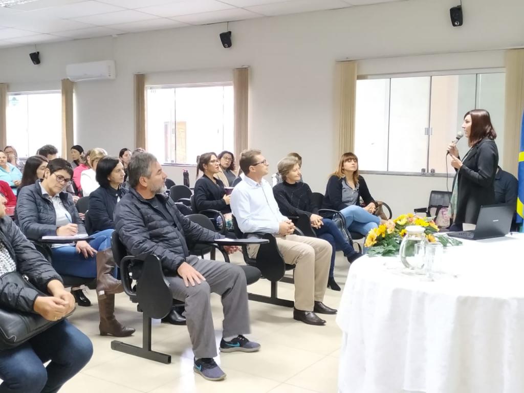 Professores assentados em uma sala, escutando a fala do chefe do núcleo