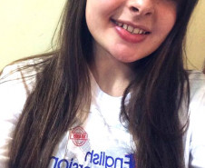 Ana Laura, do 2° ano do ensino, dá aulas de inglês para alunos das séries iniciais do ensino fundamental nas escolas municipais da sua cidade uma vez por semana há dois anos e meio