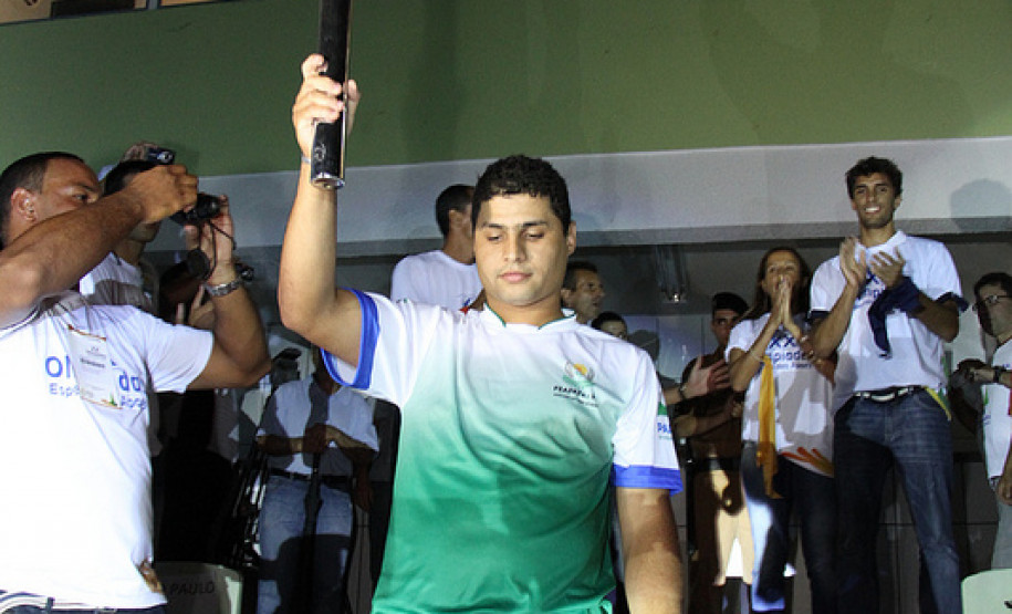 Para-atleta paranaense carregando a tocha olímpica.