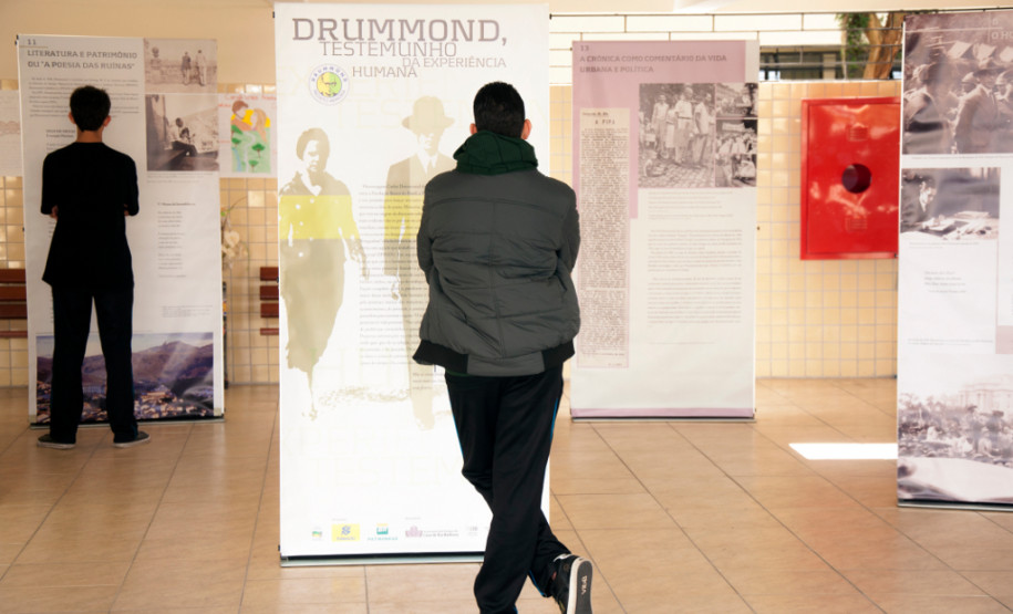 Poesia de Carlos Drumonnd percorre escolas estaduais Exposição itinerante leva 15 banners de dupla face com biografia e principais textos do poeta para escolas que trabalham a obra de Drummond.