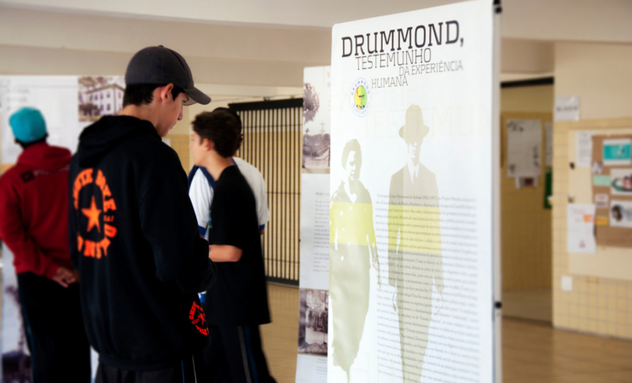 Poesia de Carlos Drumonnd percorre escolas estaduais Exposição itinerante leva 15 banners de dupla face com biografia e principais textos do poeta para escolas que trabalham a obra de Drummond.