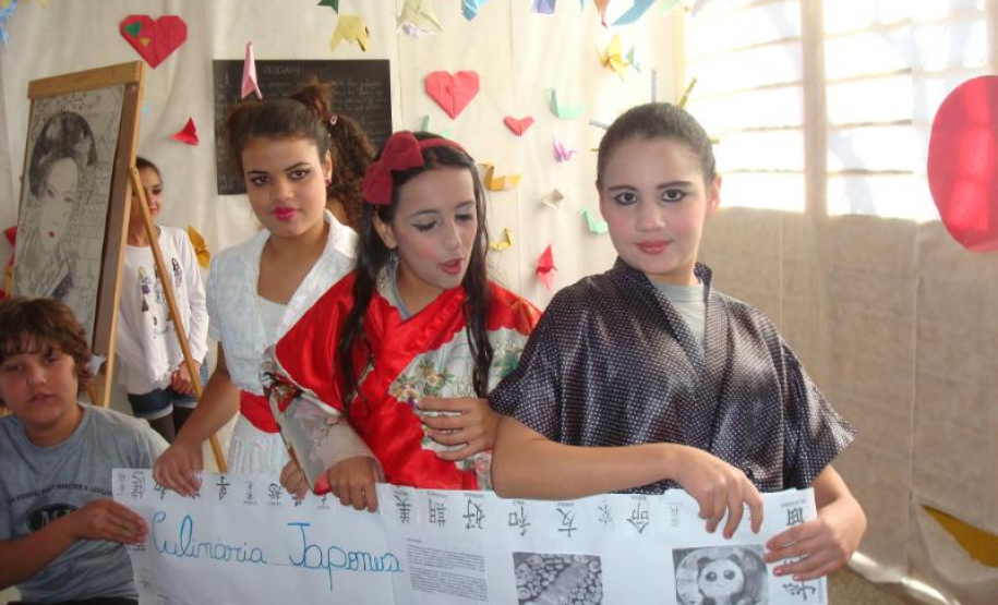 Alunas a caráter expondo materiais da cultura japonesa.