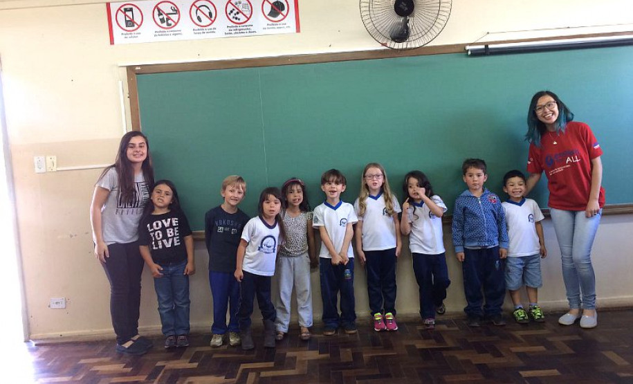 Ana Laura, do 2° ano do ensino, dá aulas de inglês para alunos das séries iniciais do ensino fundamental nas escolas municipais da sua cidade uma vez por semana há dois anos e meio