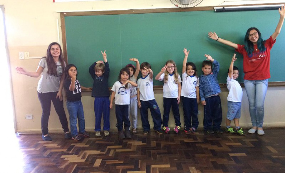 Ana Laura, do 2° ano do ensino, dá aulas de inglês para alunos das séries iniciais do ensino fundamental nas escolas municipais da sua cidade uma vez por semana há dois anos e meio