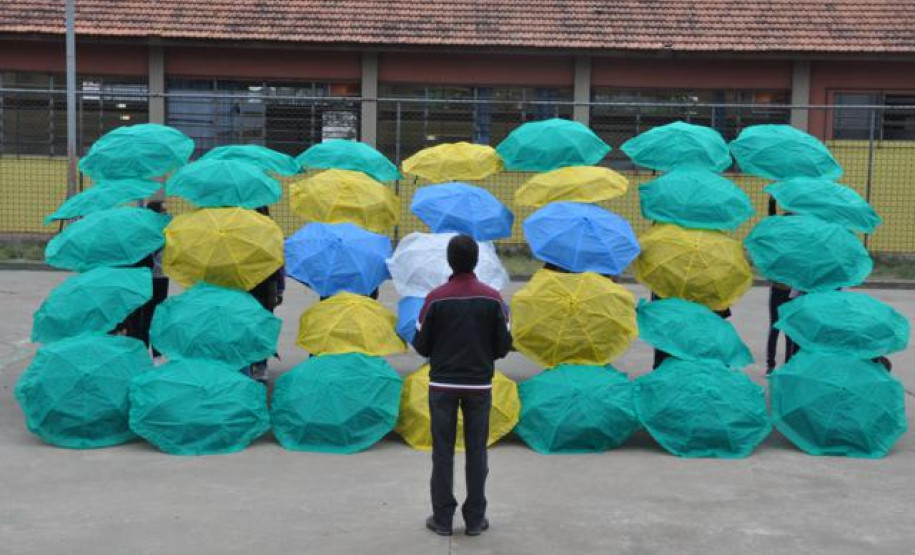 Alunos do Colégio Estadual Aníbal Khury Neto durante ensairo do mosaico da bandeira nacional feito com guarda-chuvas coloridos.