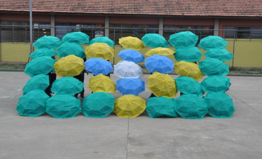 Alunos do Colégio Estadual Aníbal Khury Neto durante ensairo do mosaico da bandeira nacional feito com guarda-chuvas coloridos.